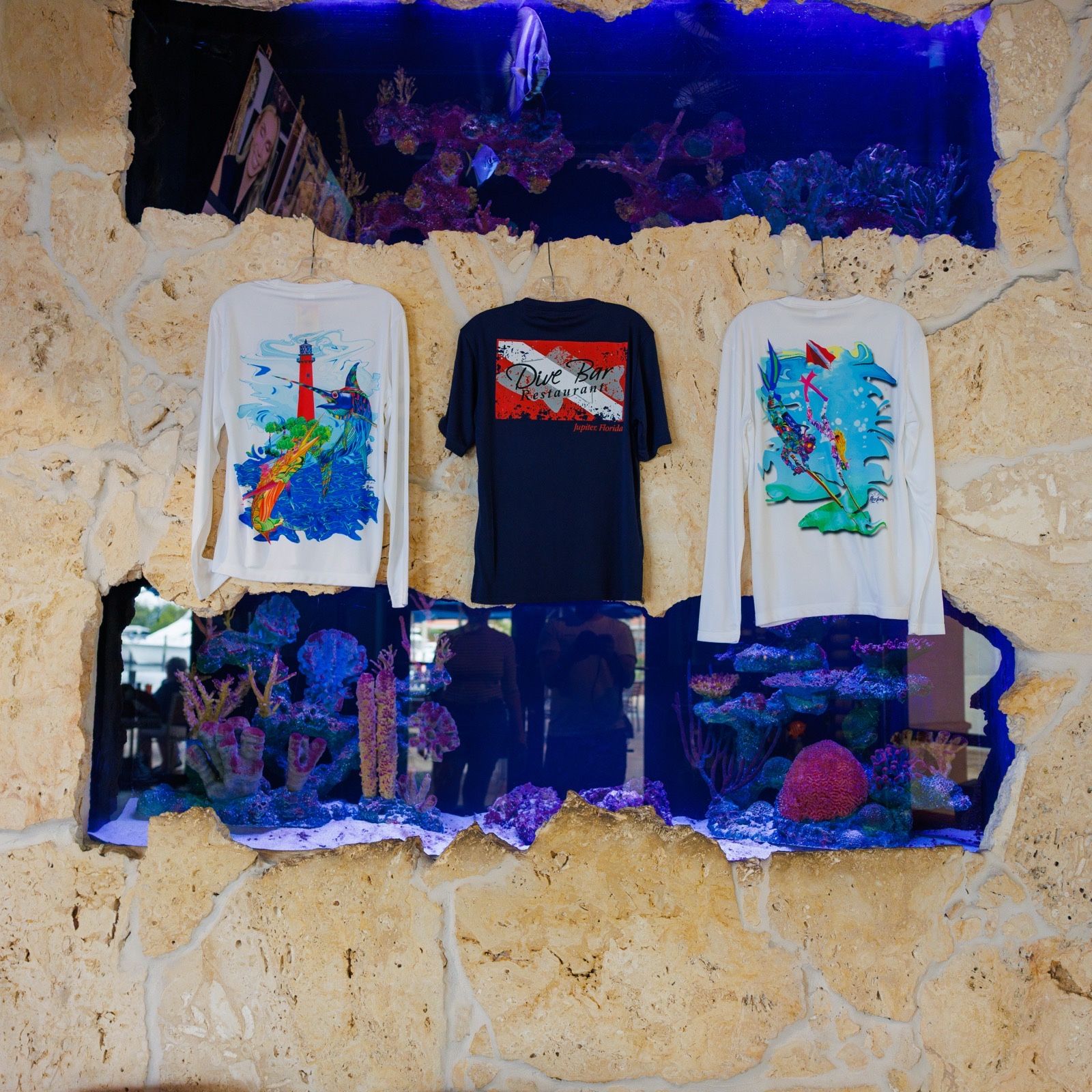 Dive Bar T-shirts hanging in front of the saltwater aquarium