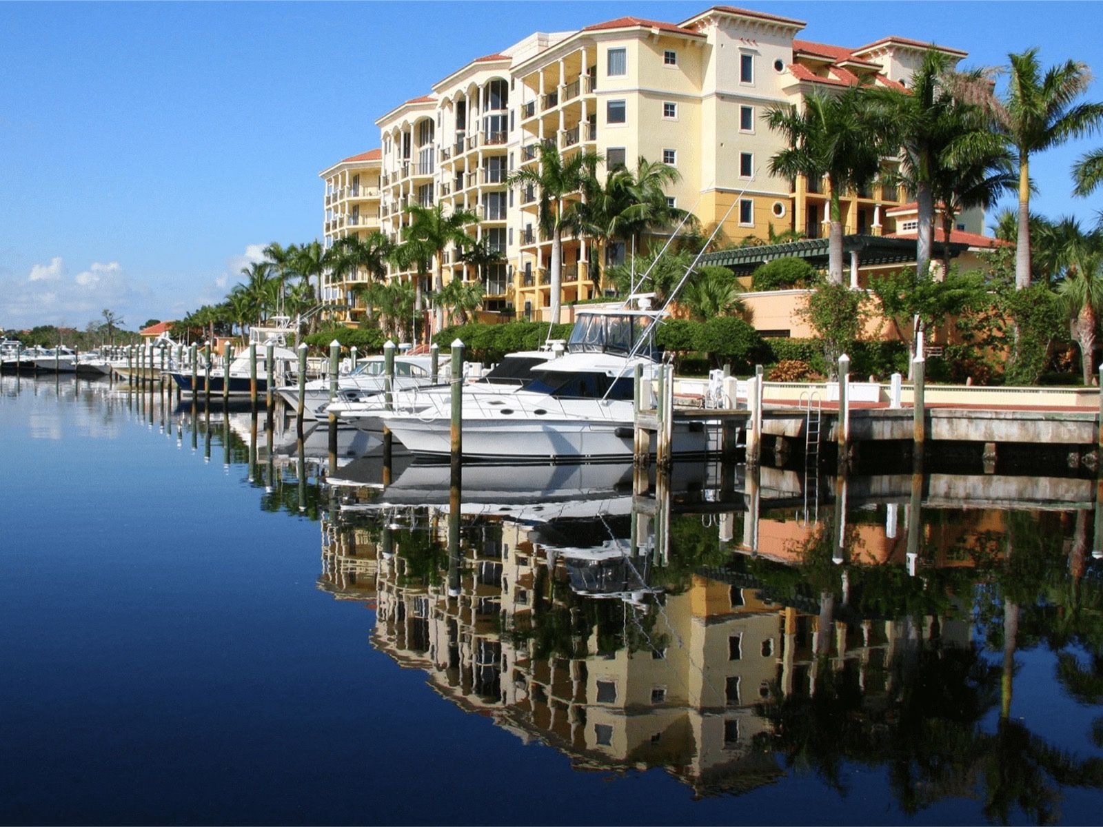 Boats docked along the Jupiter Yacht Club Marina, reflected in calm water