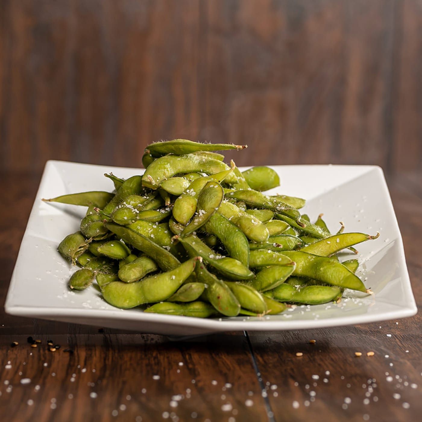 A plate of salted edamame on a wooden table at Dive Bar Restaurant